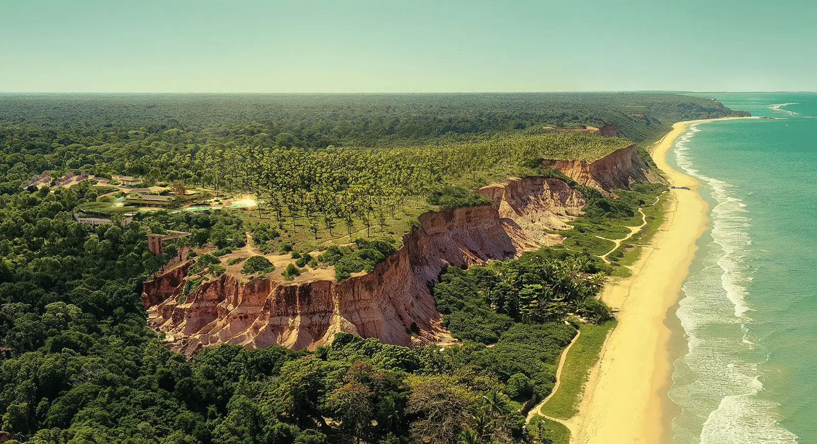 Vista aérea das falésias e da faixa de areia da Praia de Taípe, com a mata no alto e o mar verde ao lado