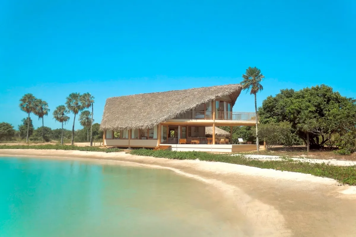 Casa de telhado de palha à beira de uma lagoa de água doce no Vila Carnaúba, na Praia do Preá, entre carnaubais